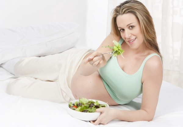Беременная женщина кушает салат