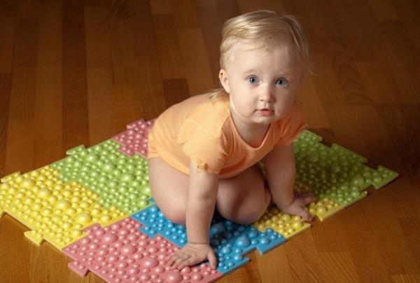 Ребенок сидит на ортопедическом коврике