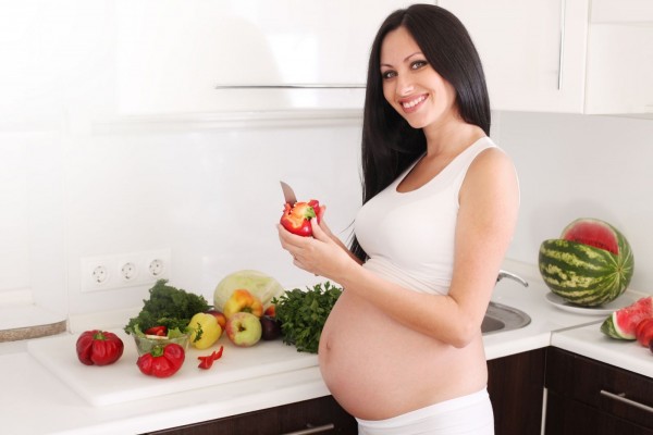 Беременная девушка чистит болгарский перец