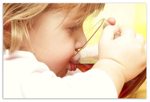 Ребенок пьет чай из кружки.