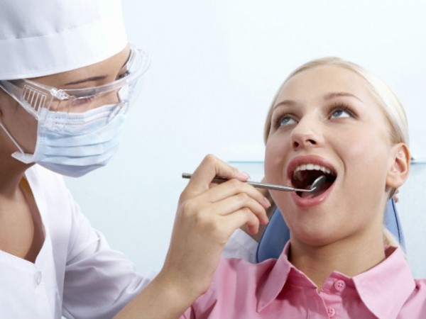 Стоматолог лечит девушке зуб