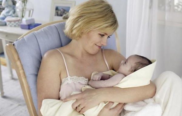 женщина держит на руках своего новорожденного ребенка
