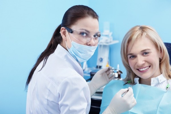 Зубной врач собирается лечить зуб молодой девушке